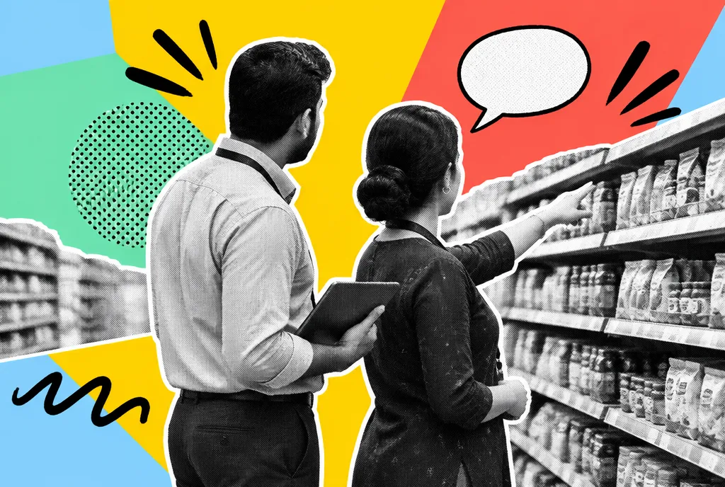 A retail executive standing in a store aisle reviewing products on the shelves while talking with a member of the team.